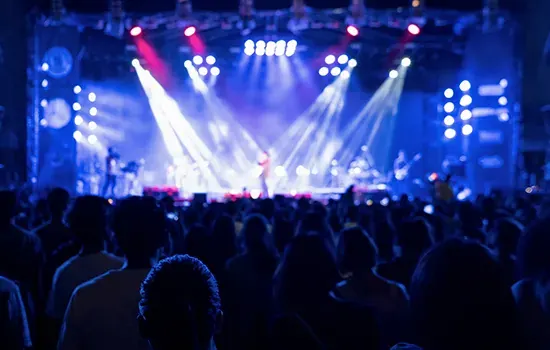 A crowd in front of a lit concert stage